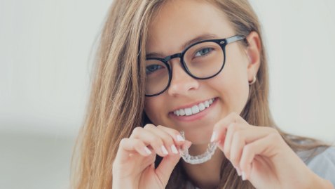 Smiling woman placing Invisalign clear braces tray