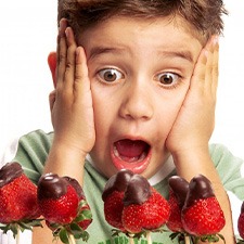 Child looking at chocolate-covered strawberries with shock and delight