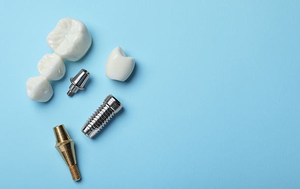 Dental bridge, crown, and implants on light blue surface