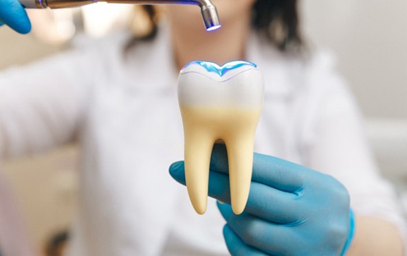 a dentist holding a large tooth with an UV light shining on top of it