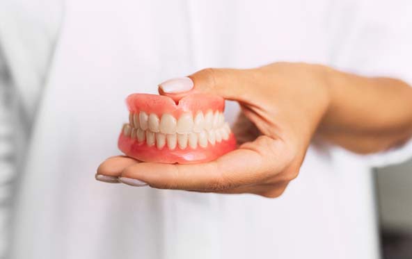 Closeup of dentist holding full dentures in Fuquay-Varina