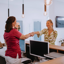 Smiling dental receptionist and patient shaking hands in lobby