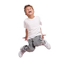 Jumping, hyperactive little boy in white shirt against white background