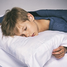 Young boy in bed, sleeping on his stomach