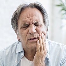 Man with jaw pain holding cheek in pain