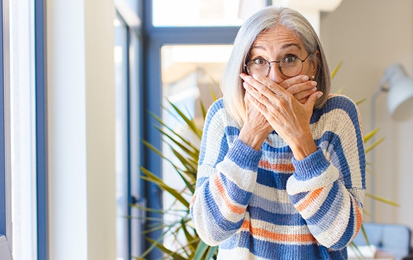 Fearful patient in need of nitrous oxide sedation dentistry covering her mouth