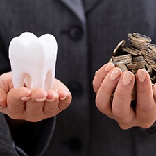Tooth and coins balanced in hands