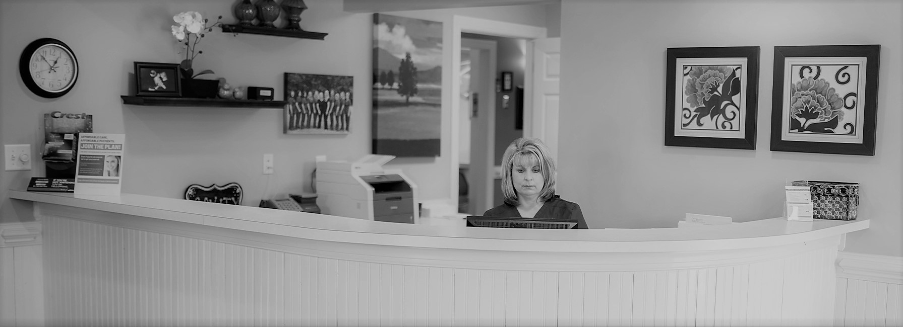 Friendly dental team member sitting behind welcoming reception desk