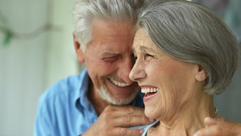 Man and woman smiling after replacing missing teeth