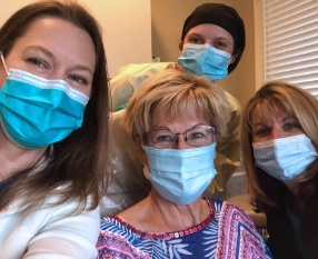 Three dental team members and dentistry patient in dental treatment room