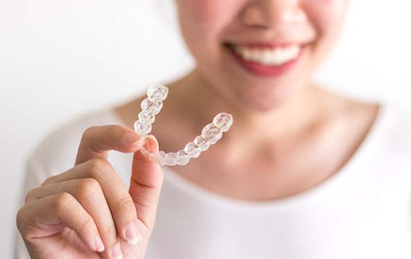 Closeup of patient holding Invisalign in Fuquay-Varina