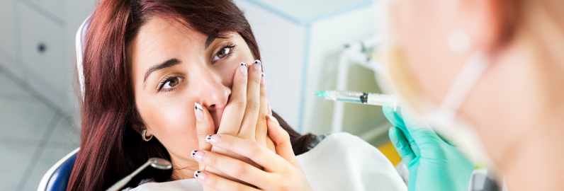 Fearful patient in need of sedation dentistry covering her mouth