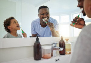 Father and son brushing teeth together
